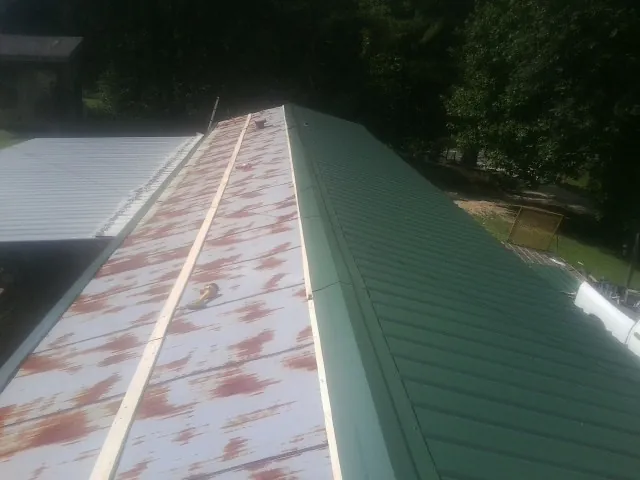 Old rusted panels beside newly installed green metal roofing — Wind Damage Roof Repair by Roofing Brothers in Perrysville