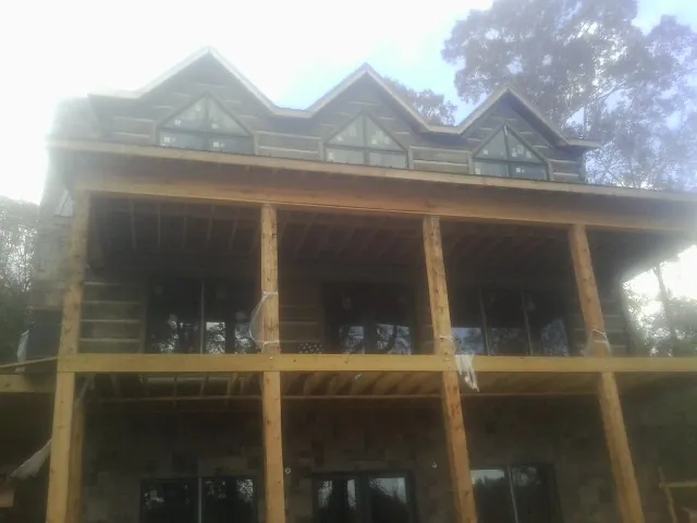 Dormers and porch framing on a large log home under construction — Roof Coating work by our crew in Perrysville
