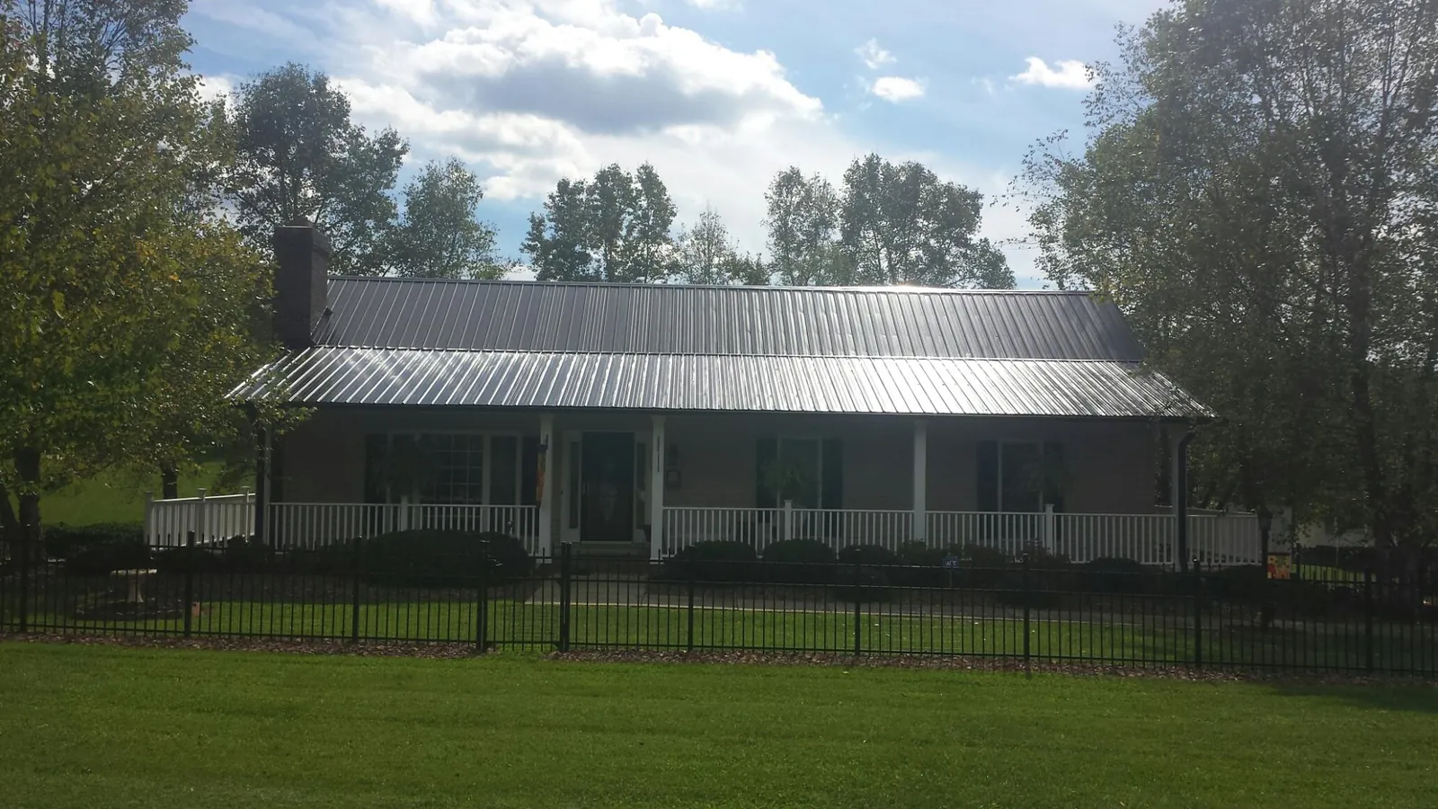 Gray metal roof on a brick ranch with a full width front porch — Gutter Guard Installation work by our crew in Perrysville