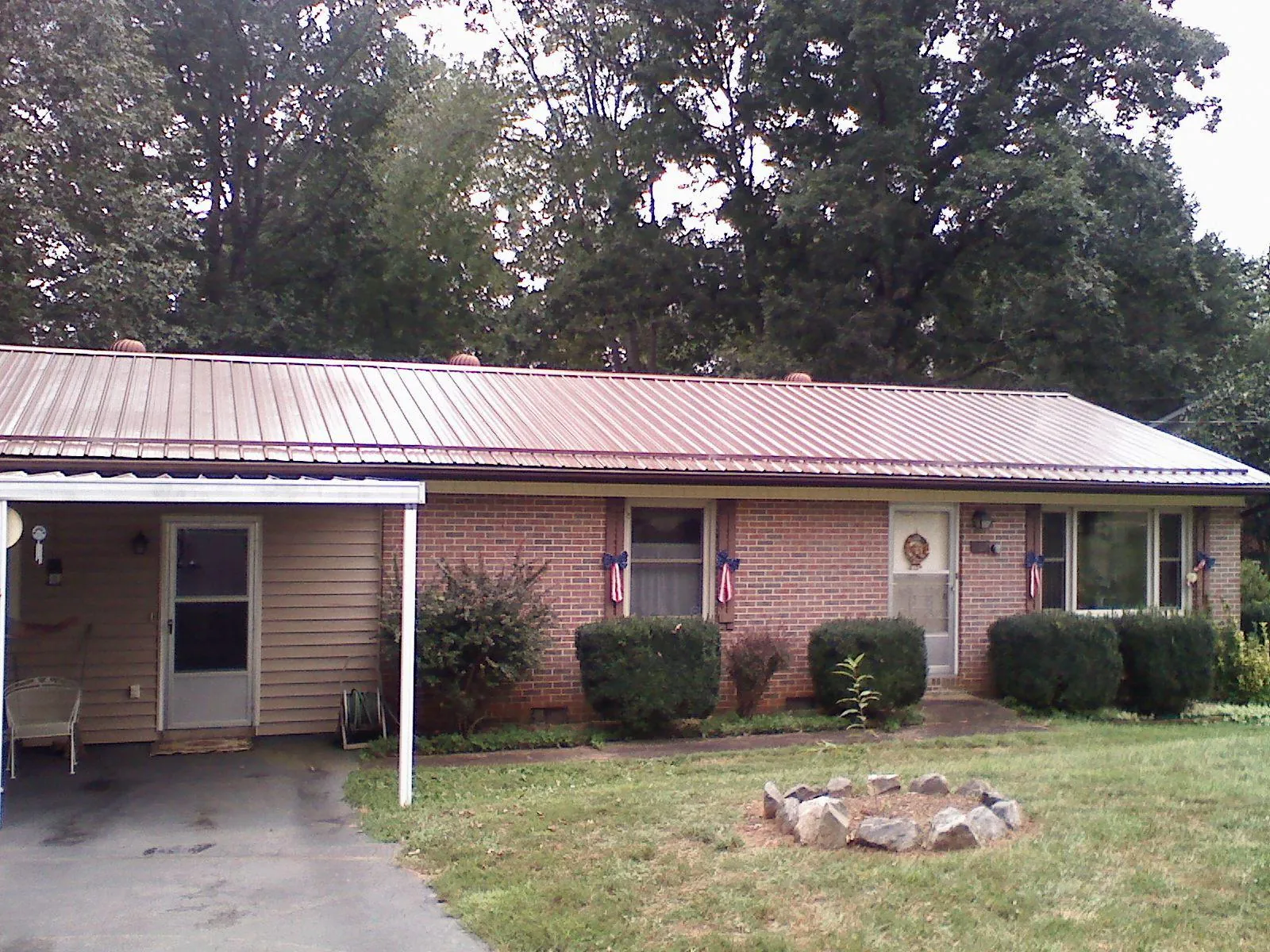 Bronze metal roof and carport on a brick ranch home — Roof Repair work by our crew in Perrysville