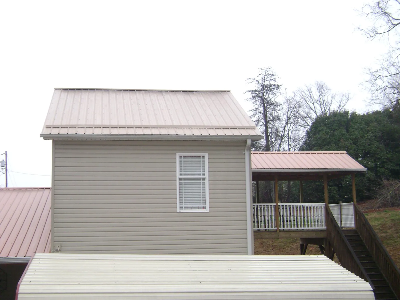 Tan metal roofs on a two story addition and attached porch, from a Roof Replacement job in Perrysville