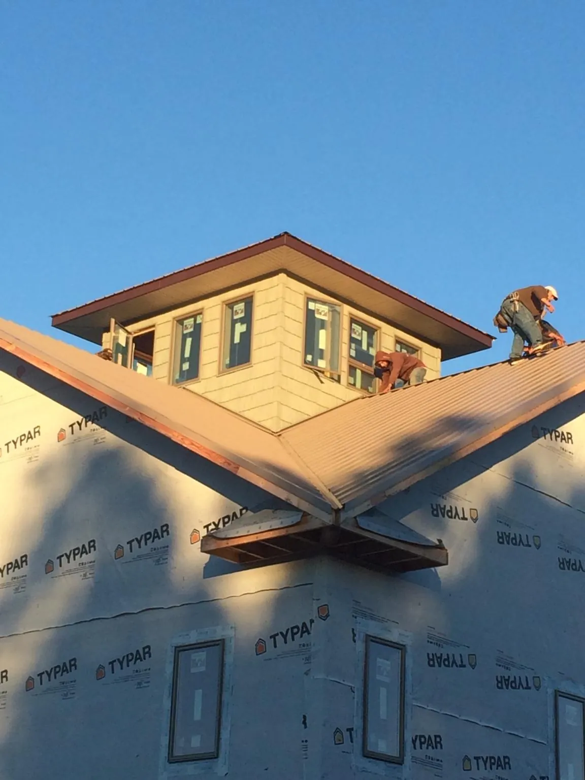 Roofers working around a rooftop cupola on a new metal roof at sunset — Roof Waterproofing in Perrysville by Roofing Brothers